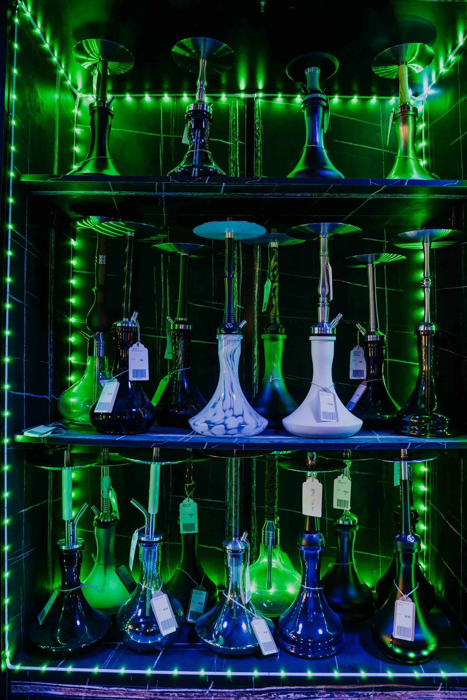 Estantería de cachimbas iluminada solo con tiras de luz verde, sin ninguna luz de techo.