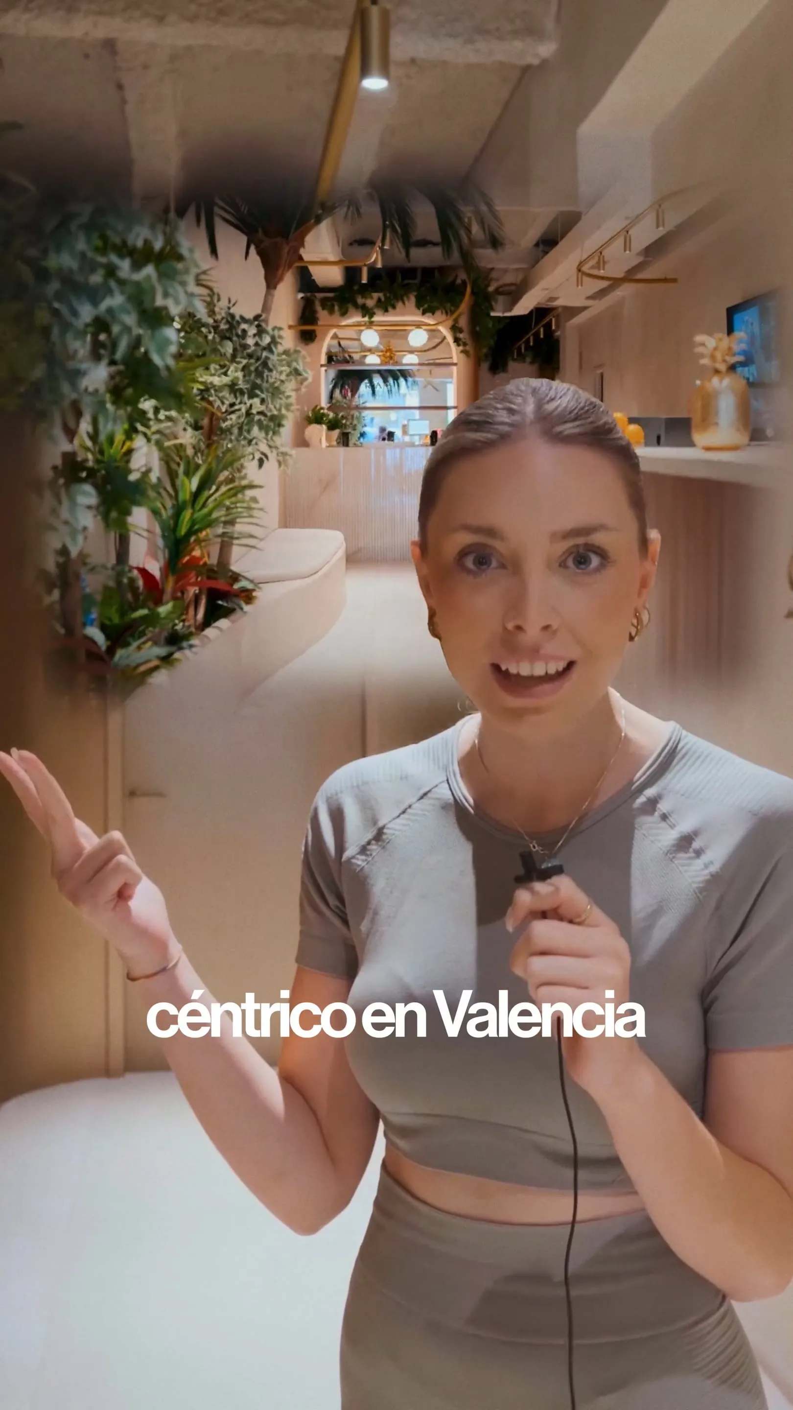 Presentadora con micrófono explicando la cabina InfraslimX en un centro de bienestar de Valencia.